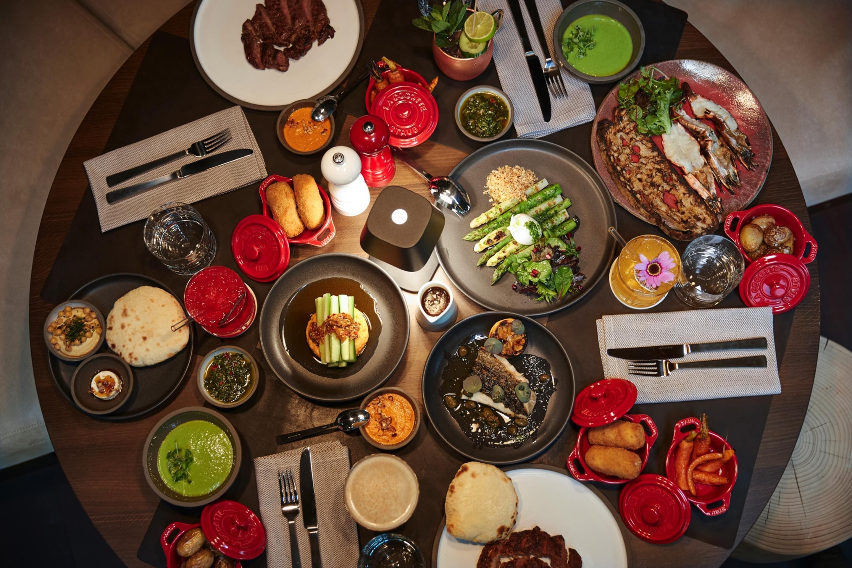 Variedad de platos y utensilios sobre una mesa, lo que sugiere un ambiente para comer.