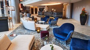 A spacious lobby with modern seating, a reception desk, and a large potted plant. - Steigenberger Hotel Hamburg (Hamburg)