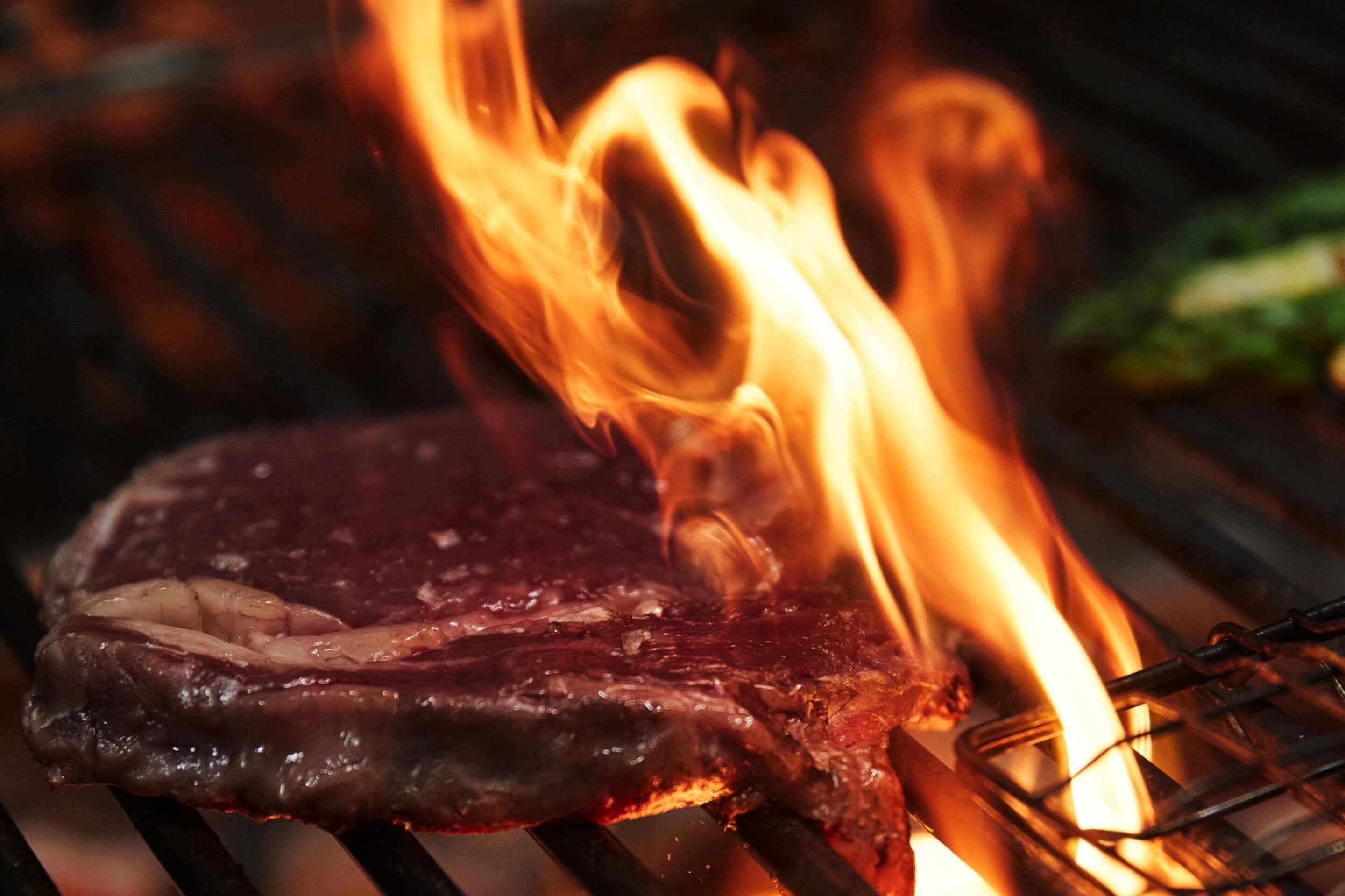 Een steak die boven een open vuur wordt gebakken.