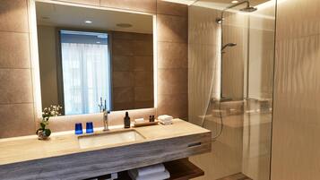 A modern bathroom with a large mirror, a sink, and a glass-enclosed shower.