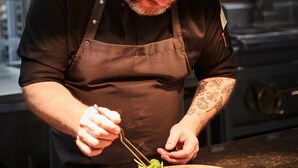 A chef preparing food in a kitchen with hanging lights and stainless steel appliances. - Steigenberger Hotel Hamburg (Hamburg)