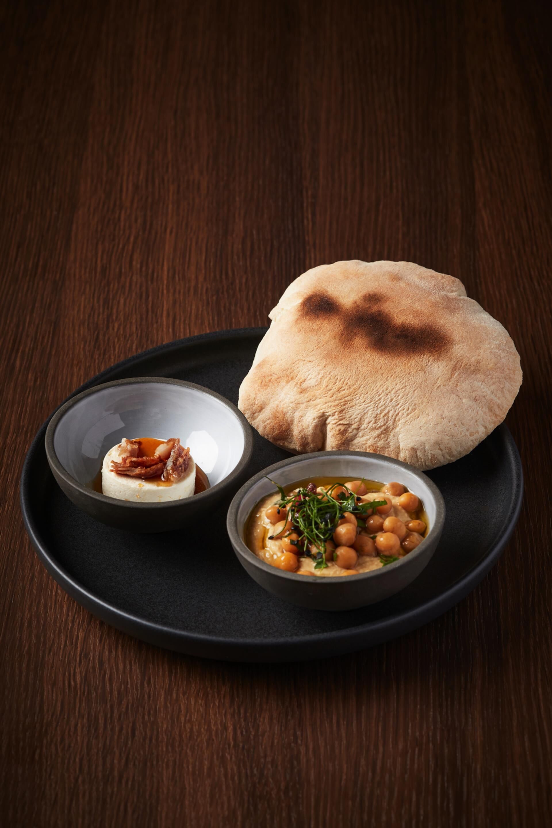 A plate with flatbread, a bowl of chickpeas, and a small bowl of sauce.