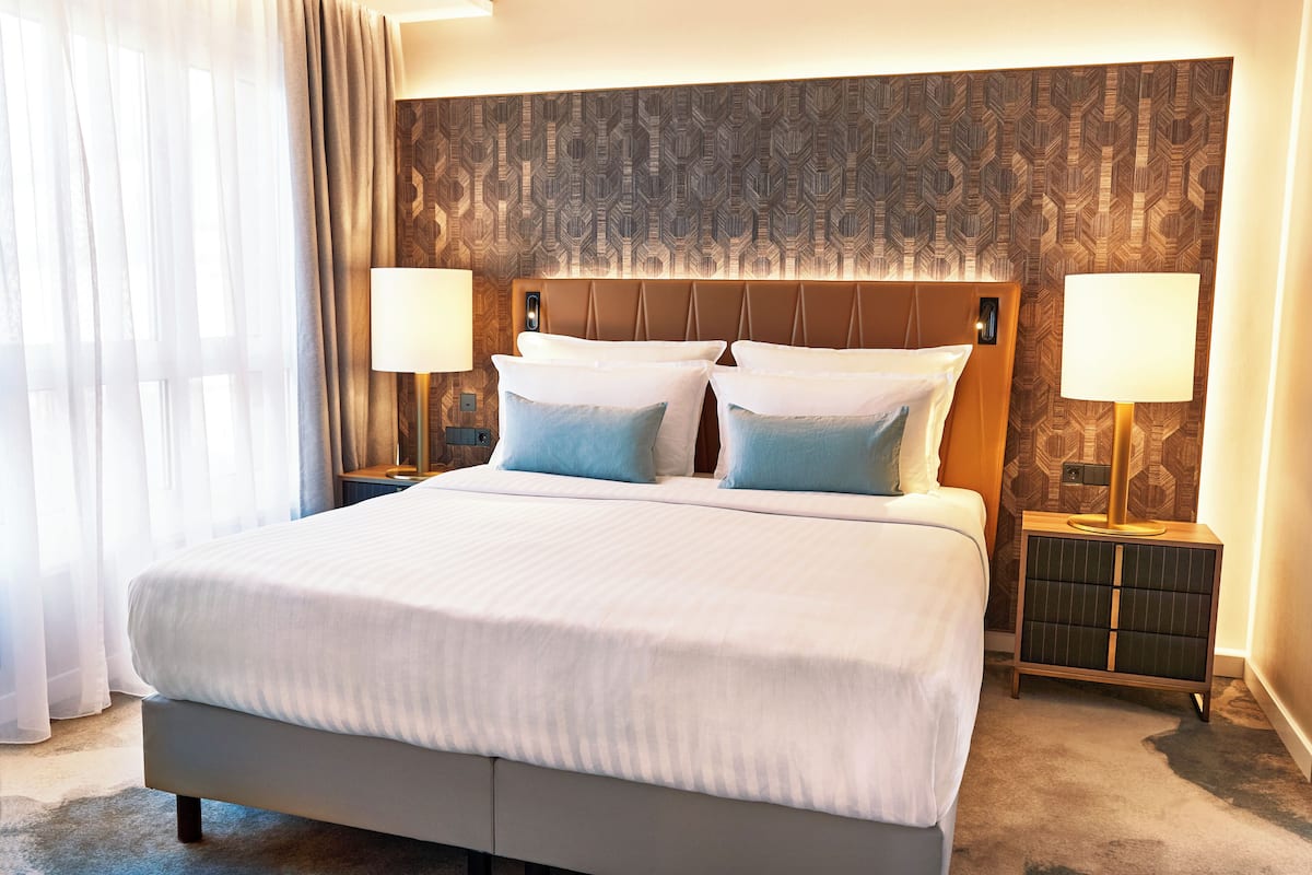 Une chambre d’hôtel avec un grand lit, deux tables de chevet et une tête de lit à motifs.