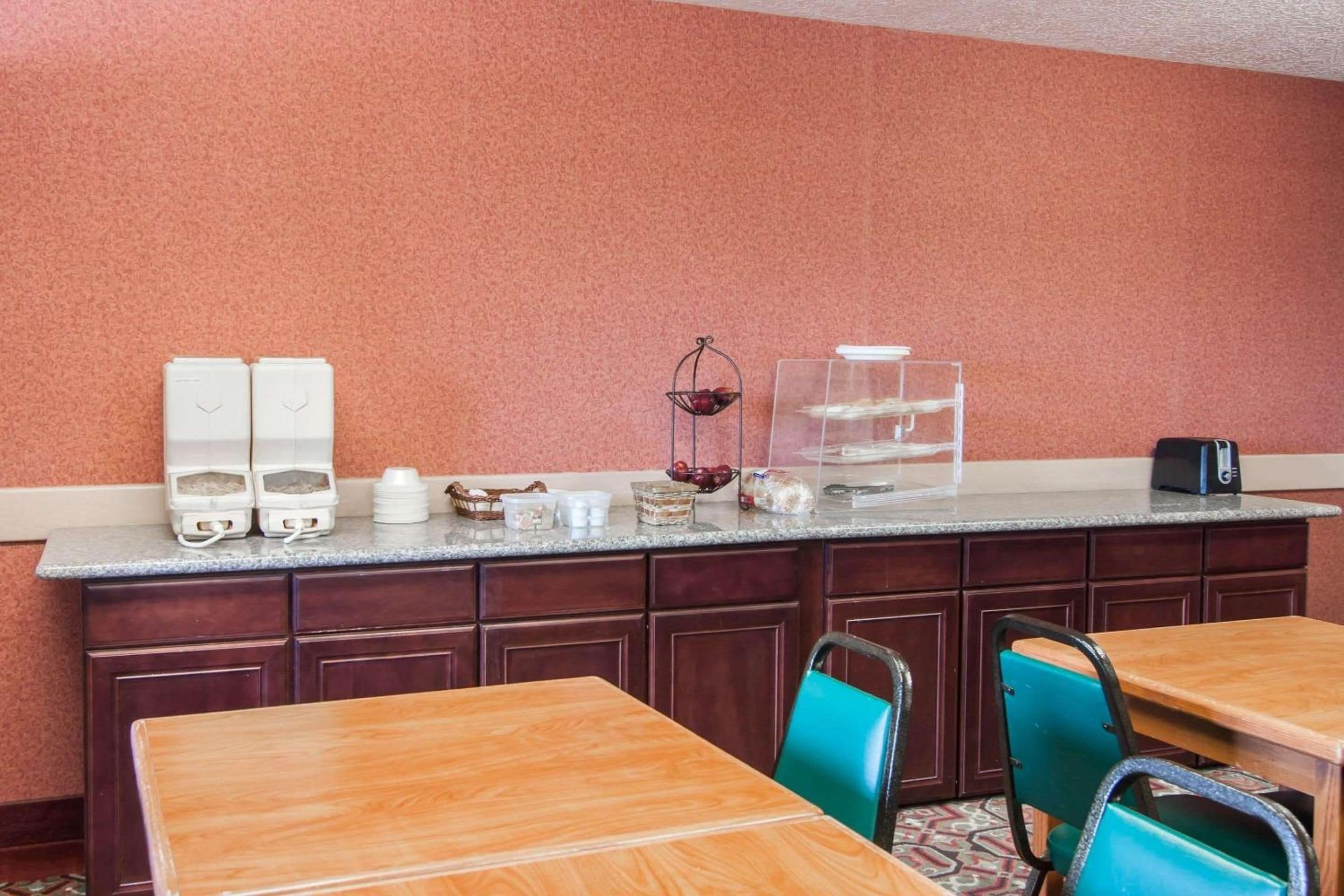 A hotel kitchenette with a marble countertop, a coffee machine, a wine cooler, and a glass display case.