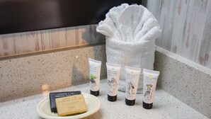 A bathroom counter with a plate of soap bars, a towel, and several tubes of body wash.