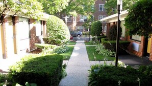 A residential street with a sidewalk, houses, and greenery.