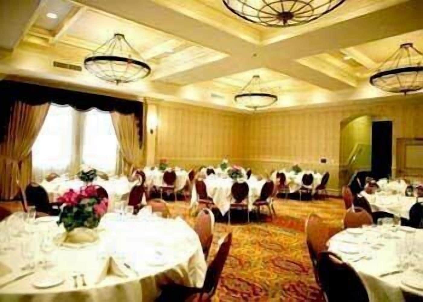 A banquet hall with round tables, white tablecloths, and floral centerpieces.