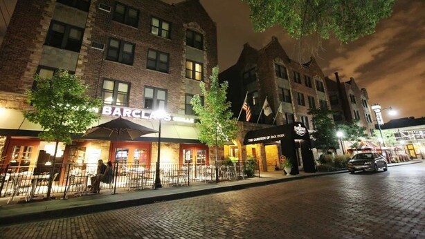 A brick building with a restaurant named "BARCLAYS" and a sign for "THE COTTAGE OF OAK BURTON."