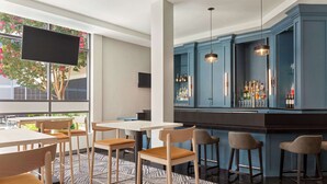 Un área de bar moderna con un armario azul, taburetes de bar y un televisor de pantalla plana montado en la pared.