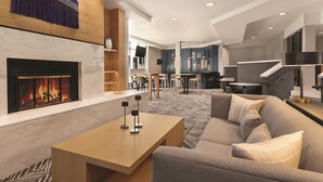 Un moderno vestíbulo de hotel con chimenea, zona de estar y una escalera.