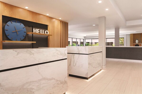 A modern reception area with a marble reception desk, a large clock, and a 'HELLO' sign.