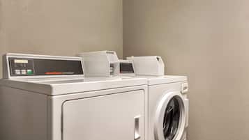 A front-loading white commercial dryer with a control panel and a front-loading washing machine.