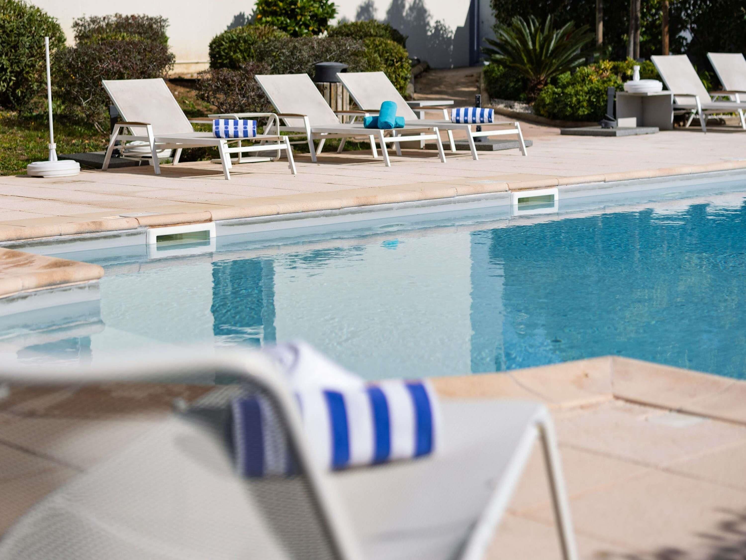 A poolside area with lounge chairs and a clear pool.