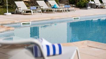 A poolside area with lounge chairs and a clear pool.