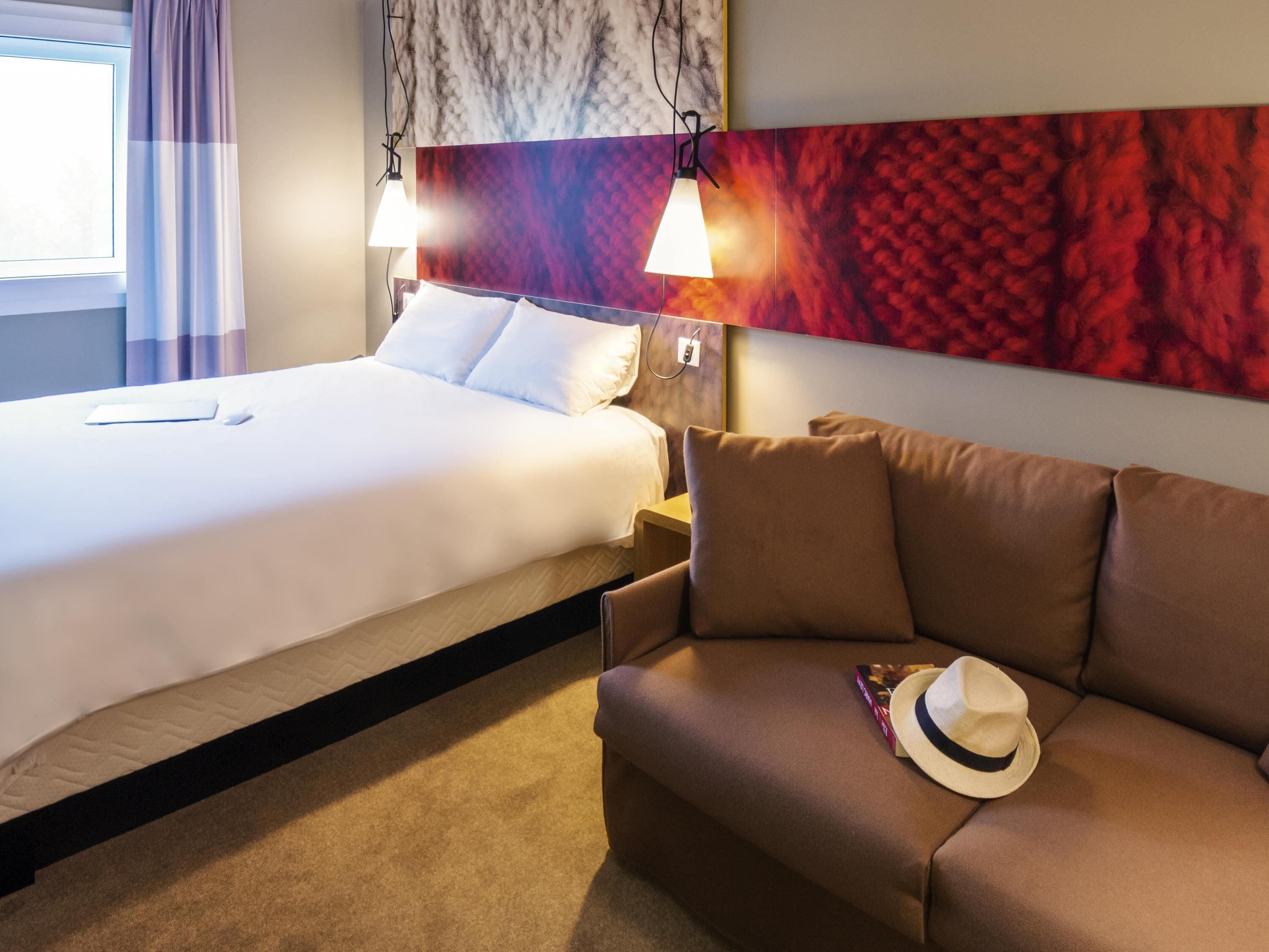 Una habitación de hotel con una cama, un sofá y una pared con un diseño texturizado.