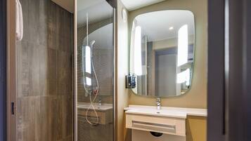 A modern bathroom with a glass-enclosed shower, a white sink, and a large mirror.