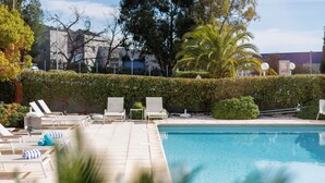 A swimming pool with lounge chairs and a hedge. - ibis Toulon La Valette (La Valette-du-Var)