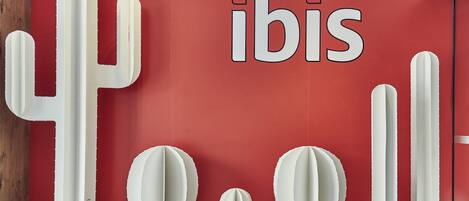 A red wall with the word "ibis" and cactus sculptures.
