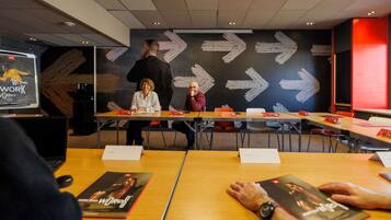 Una sala de conferències amb taules, cadires i una pantalla gran que mostra una imatge.