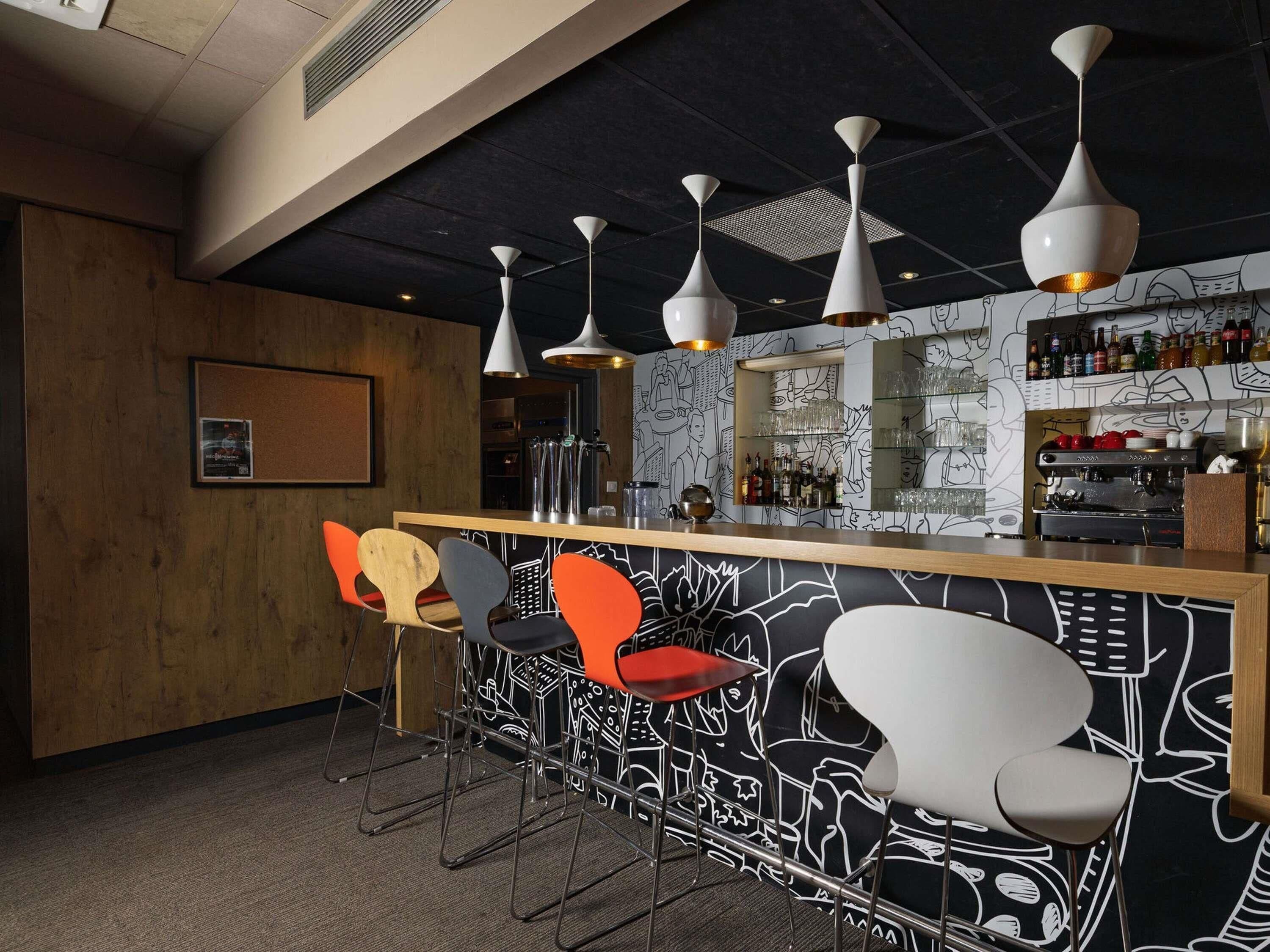 Eine Bar mit einer Holztresen, Metallbarhocker und einer Wand mit Muster.