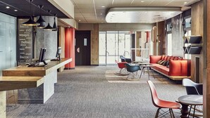 A modern interior with a reception desk, seating area, and large windows. - ibis Toulon La Valette (La Valette-du-Var)