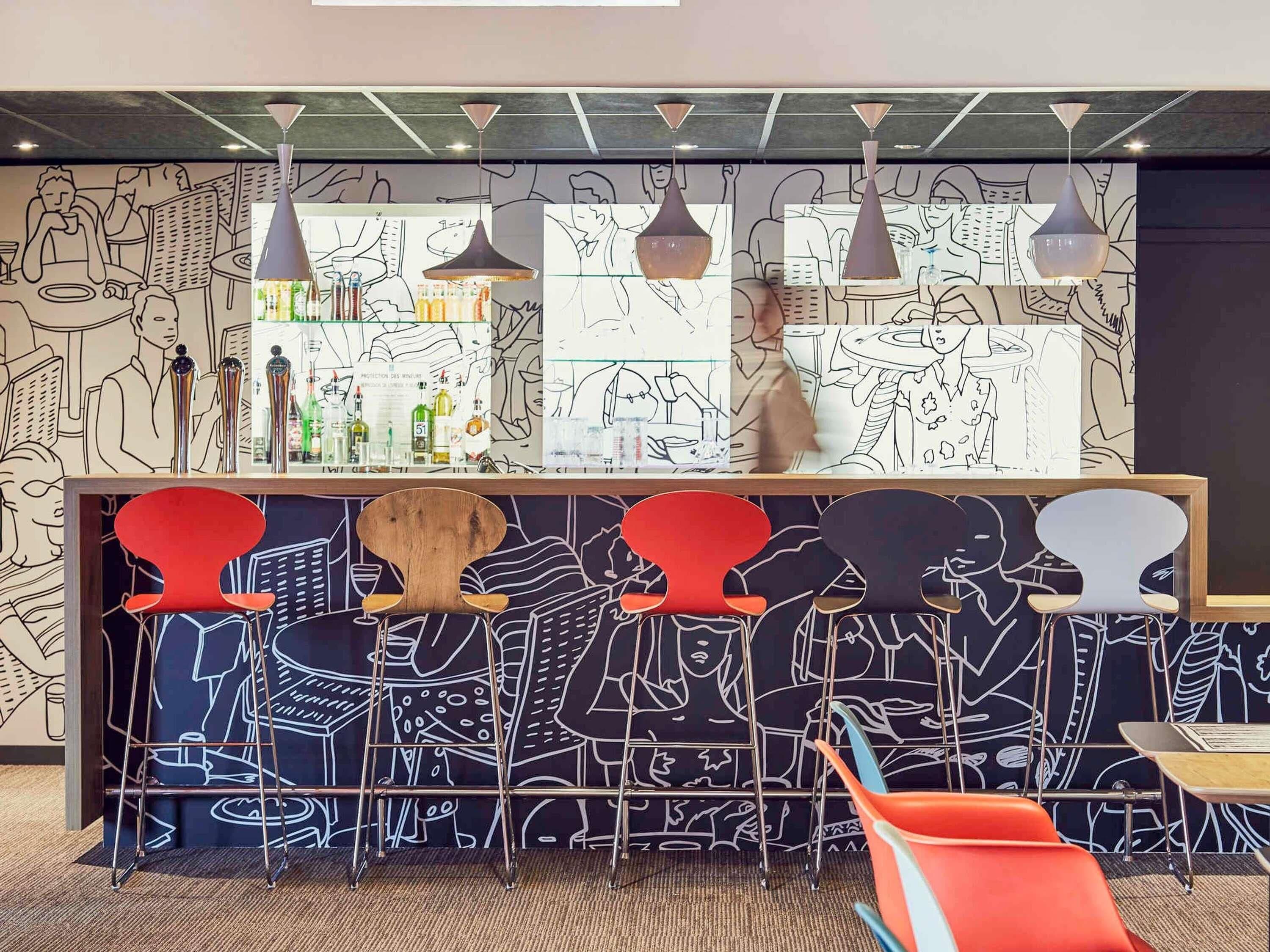 A bar area with a counter, stools, and hanging pendant lights.