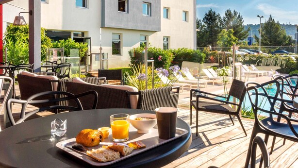 A rooftop terrace with outdoor seating, a pool, and a view of a modern building. - ibis Toulon La Valette (La Valette-du-Var)