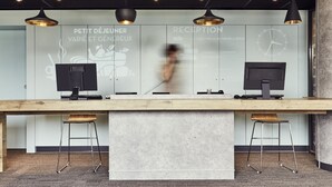 A reception desk with two computer monitors, a wooden table, and two bar stools. - ibis Toulon La Valette (La Valette-du-Var)
