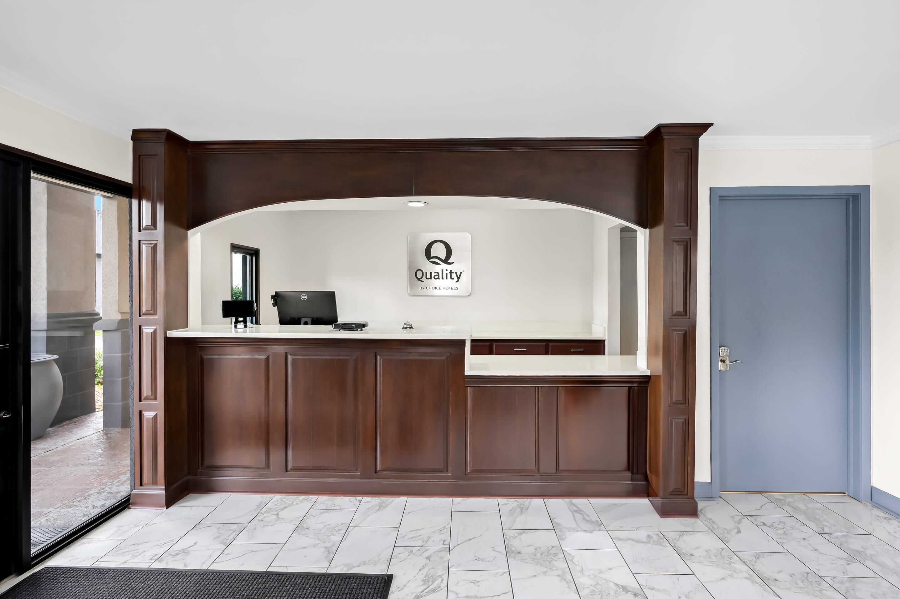 A reception desk with a sign that reads "Quality by Choice Hotels."