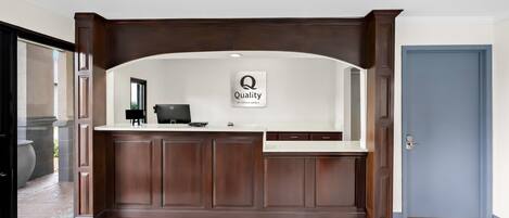A reception desk with a sign that reads "Quality by Choice Hotels."
