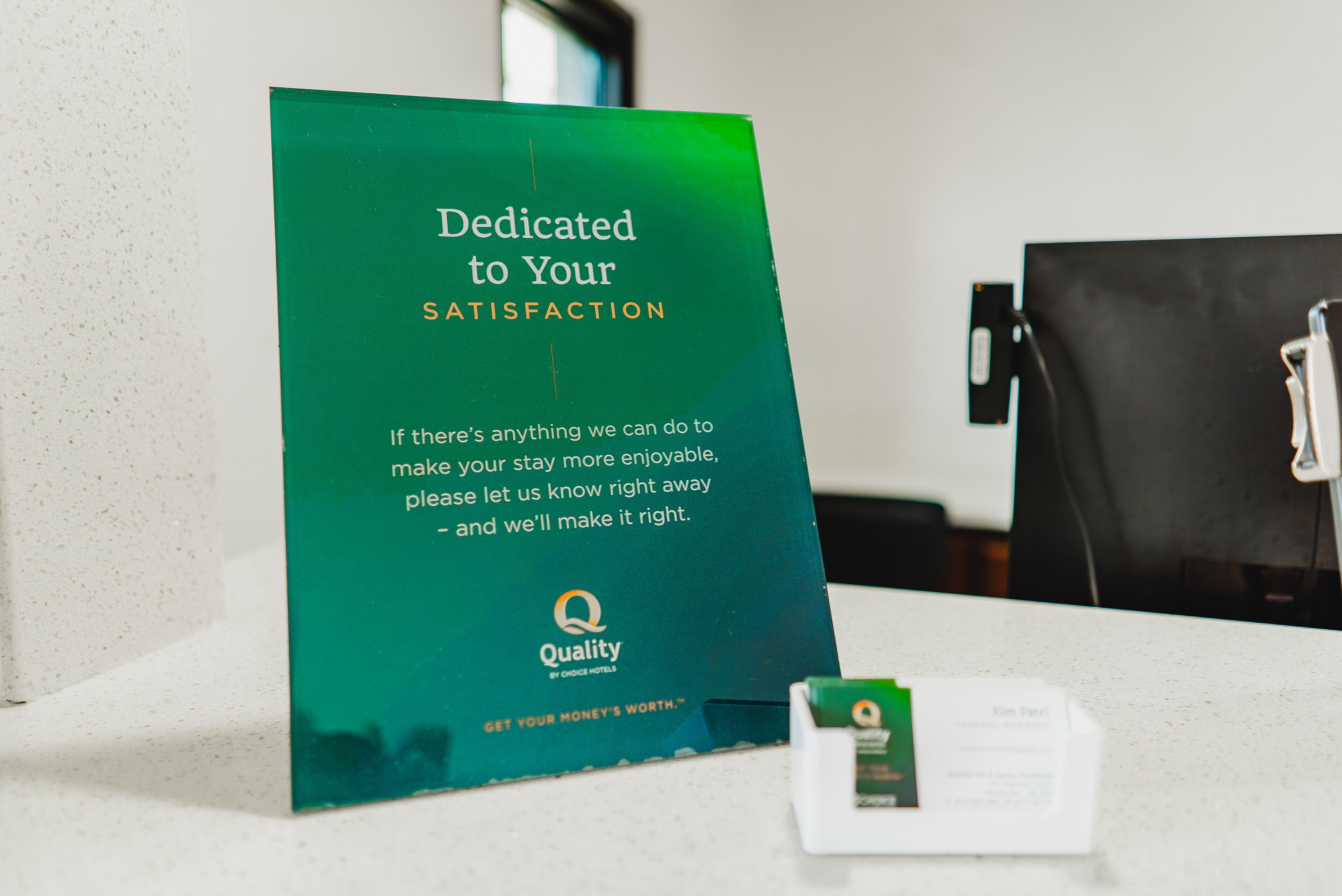 A green sign with text about dedication to customer satisfaction and a logo for Quality by Choice Hotels.