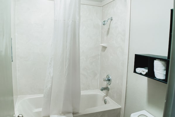 A bathroom with a bathtub, shower, and toilet.