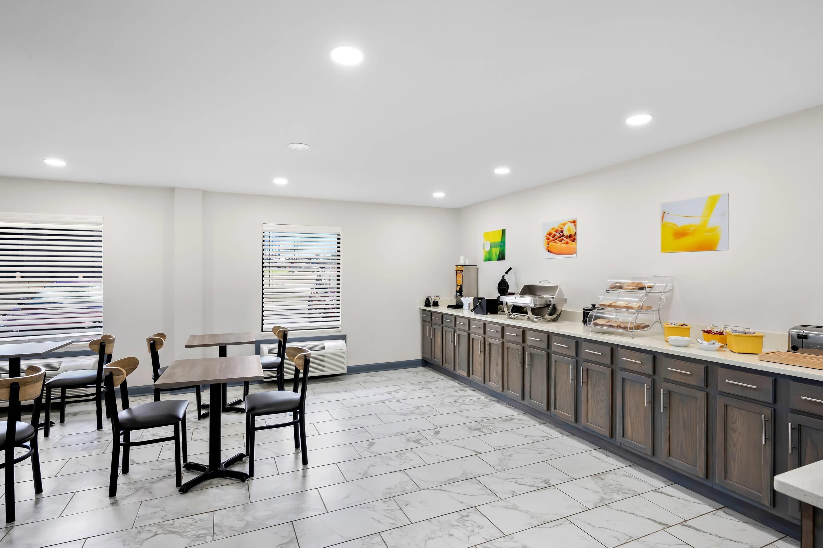 A modern kitchen with marble flooring, wooden cabinets, and a breakfast bar.