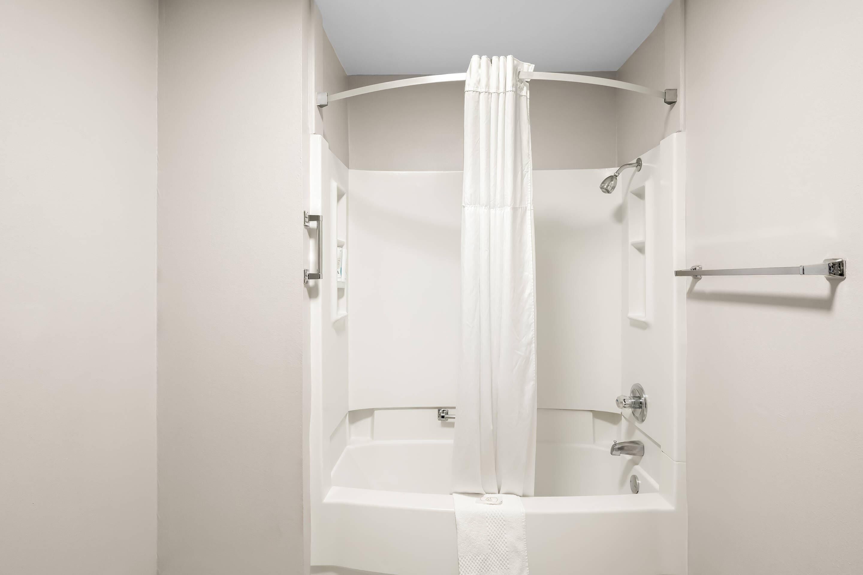 A white bathroom with a bathtub, a shower curtain, and a towel rack.