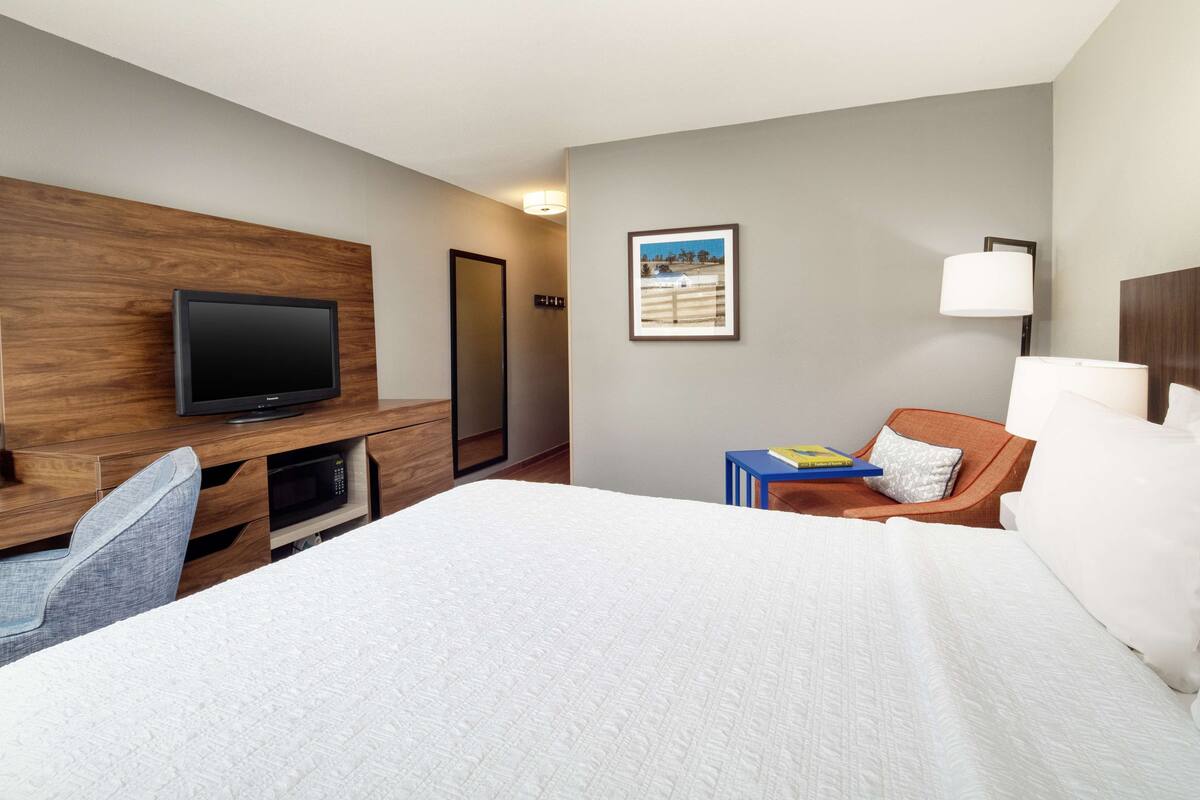 A hotel room with a bed, a TV, a desk, and a chair.