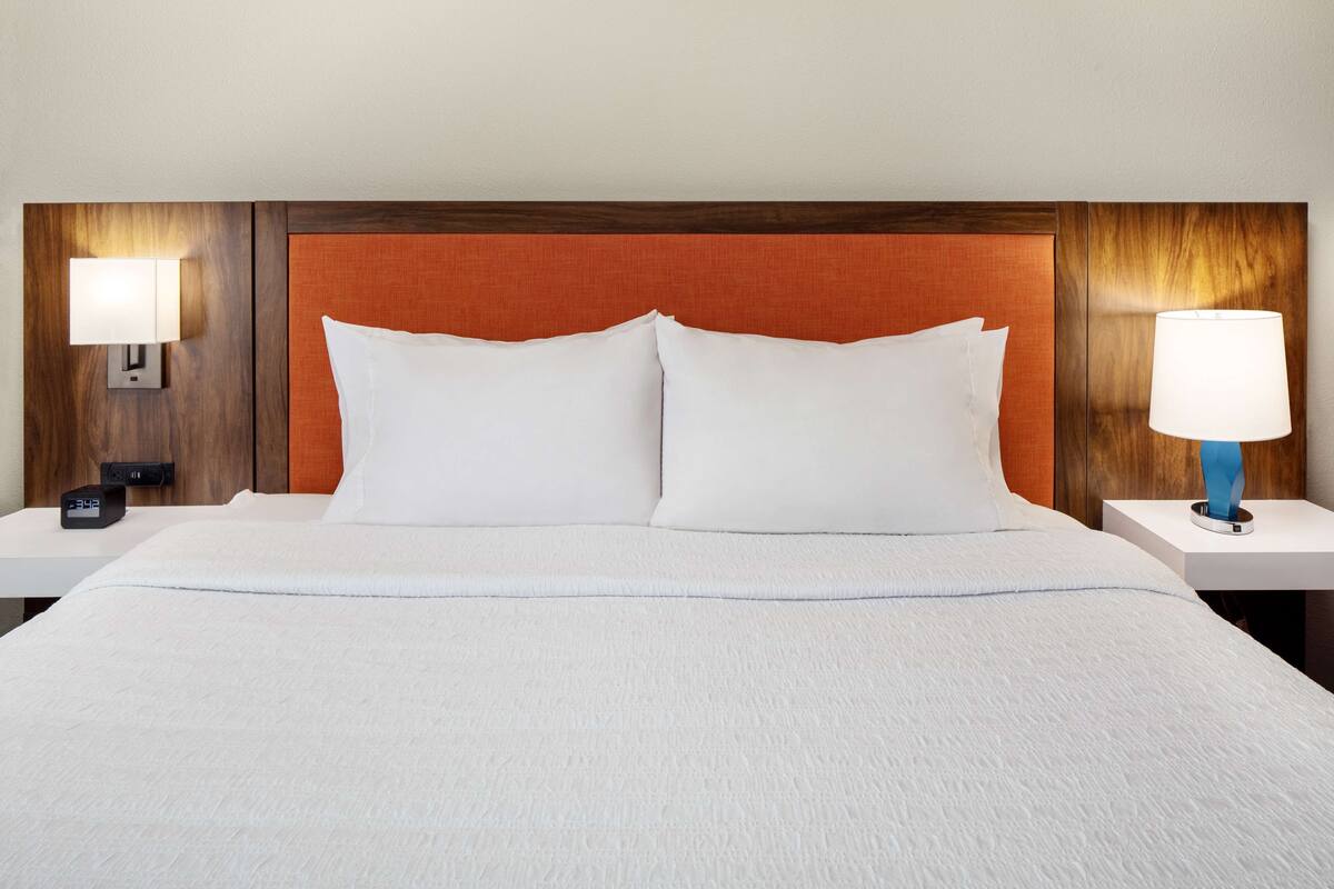 A hotel room with a large bed, two bedside tables, and a wooden headboard.