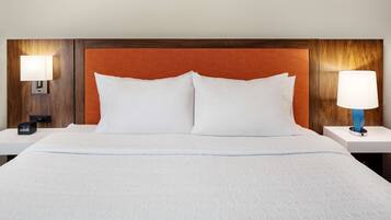A hotel room with a large bed, two bedside tables, and a wooden headboard.