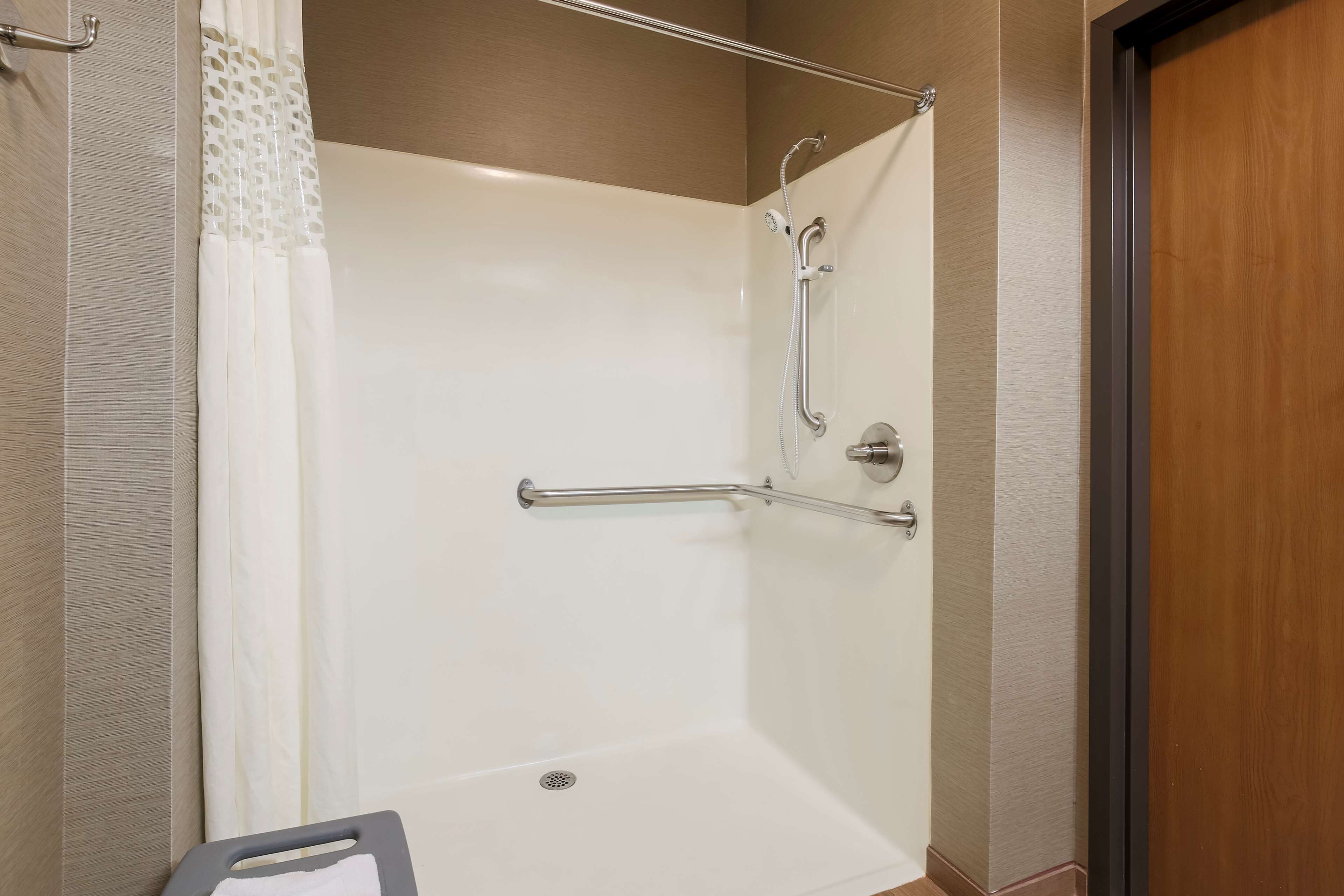 A shower area with a grab bar, a showerhead, and a curtain.