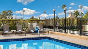 Un espace aménagé au bord de la piscine, avec des chaises longues, une piscine et une clôture.