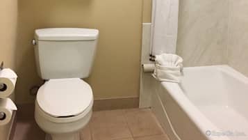 Ein Badezimmer mit Toilette, einem Handtuchhalter mit gefalteten Handtüchern, einer Duschvorhang und einer Badewanne.
