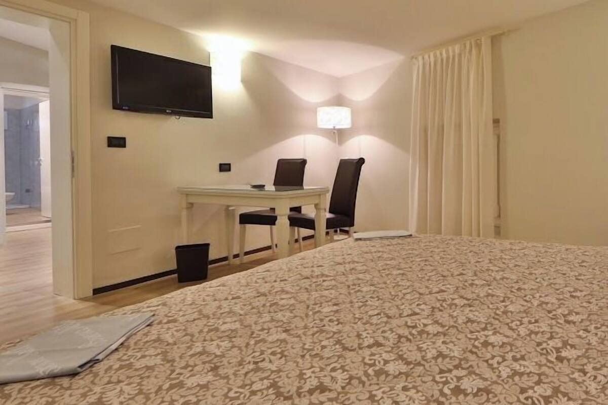 Une chambre d’hôtel comprenant un lit, un bureau avec deux chaises, une télévision et une lampe.