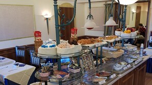 Un buffet proposant divers plats, et une personne assise à une table à l’arrière-plan.