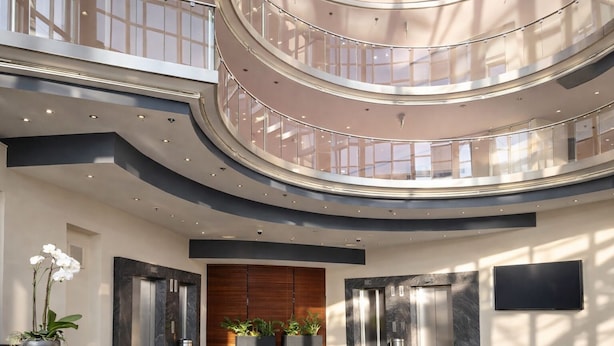 A multi-level atrium with glass railings, elevators, and potted plants. - Hotel Dresden Neustadt (Dresden)