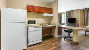 Una cocina compacta con refrigerador, microondas, estufa y gabinetes de madera.