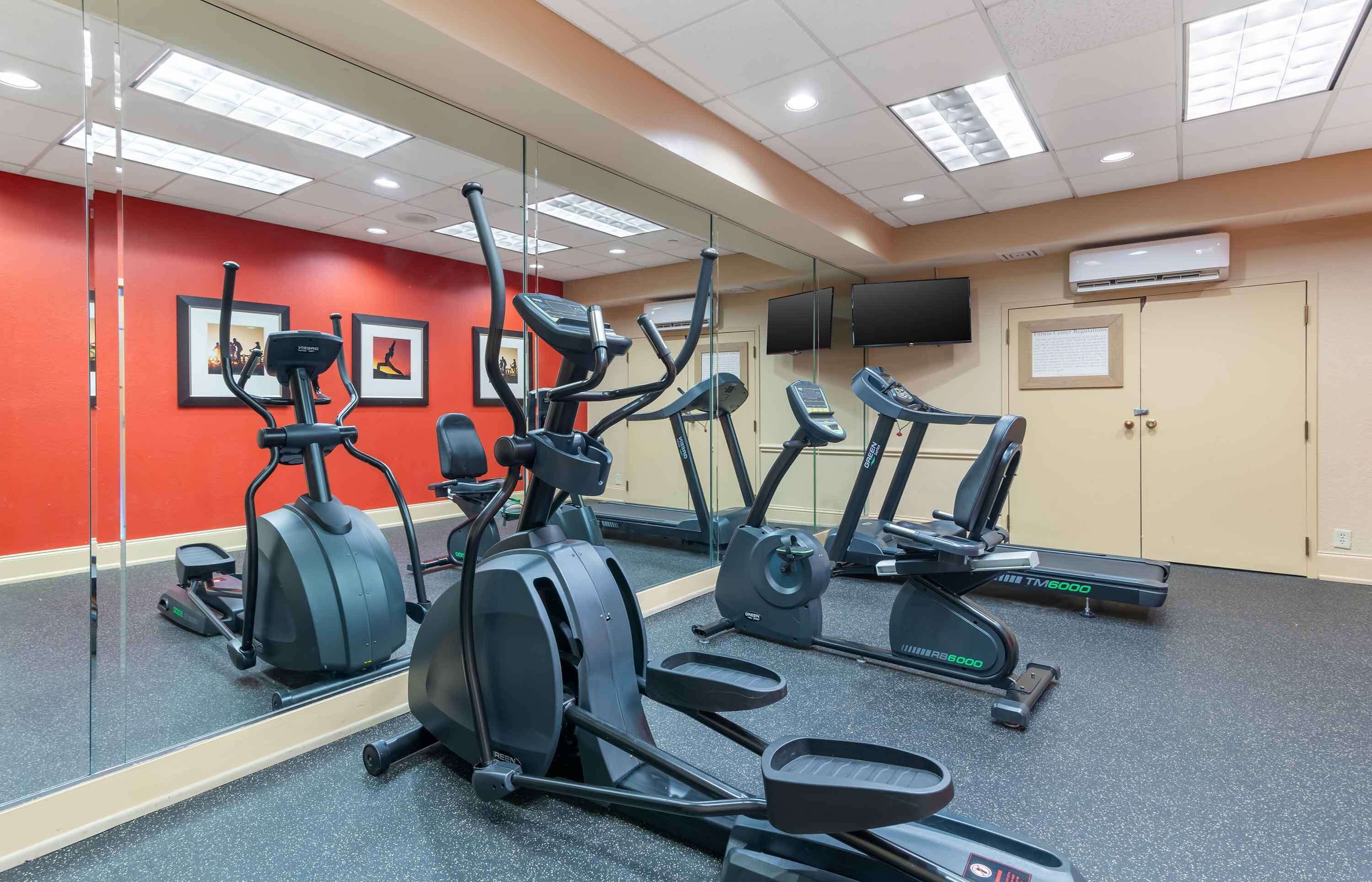 A gym with exercise equipment, a large mirror, and a red wall.