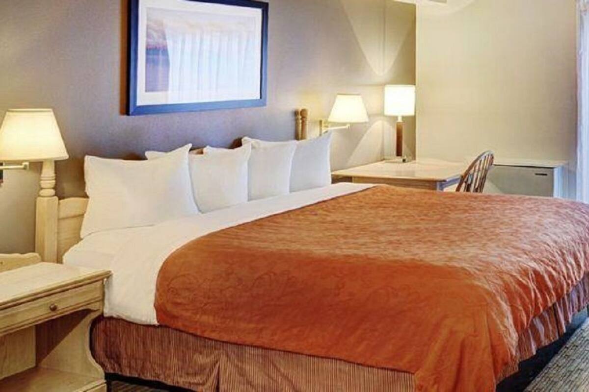 A hotel room with a large bed, two bedside tables, a desk, and a chair.