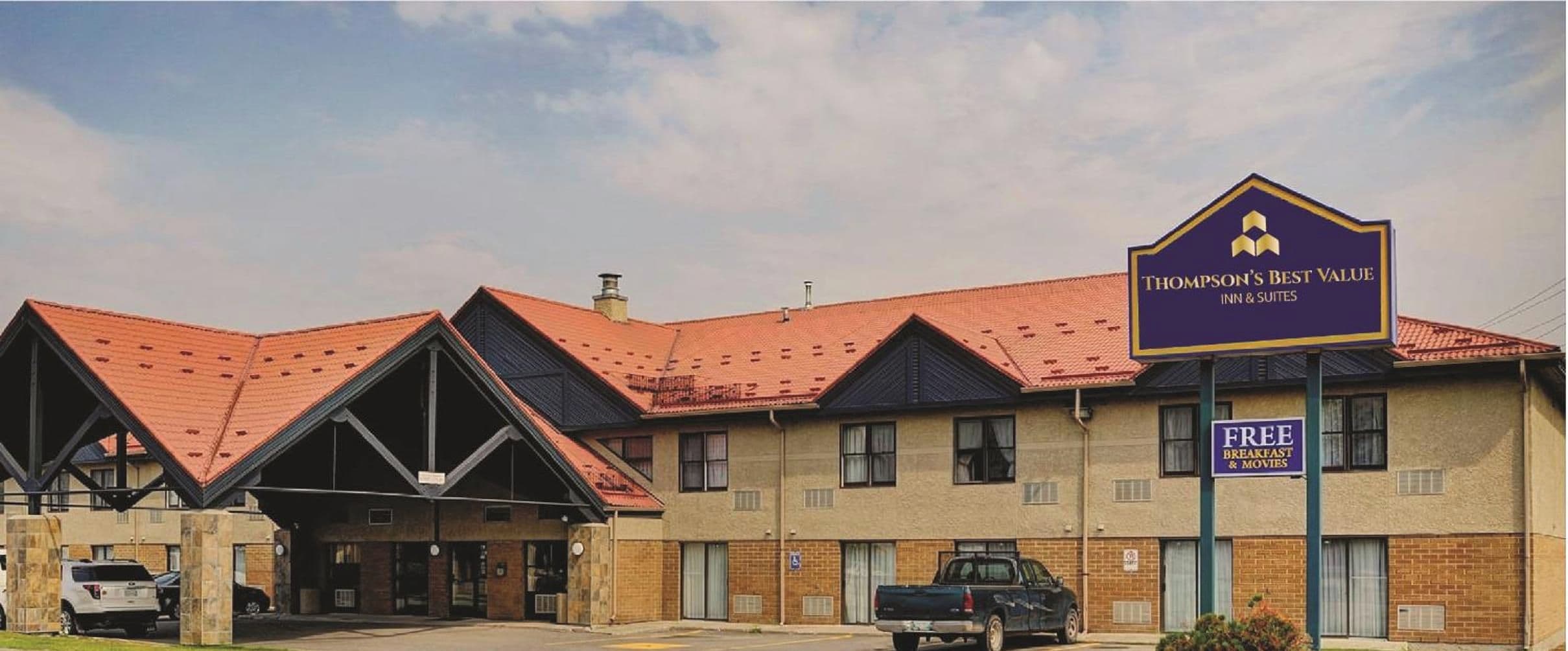 A motel with a distinctive red roof and a sign for Thompson's Best Value Inn & Suites.