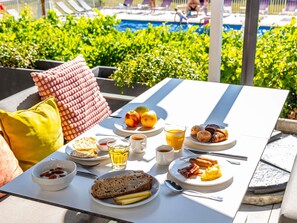 A breakfast table with plates of food, a bowl of fruit, a glass of juice, and a cup of coffee. - Novotel Dijon Sud (Marsannay-la-Cote)