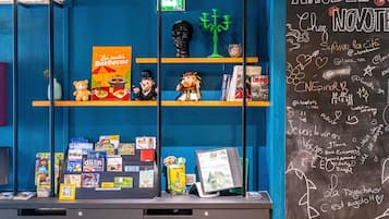 A blue wall with shelves displaying books, a QR code, and a chalkboard with writings.