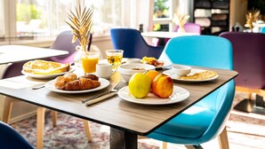 A breakfast table with plates of food, a fruit bowl, and a glass of orange juice.